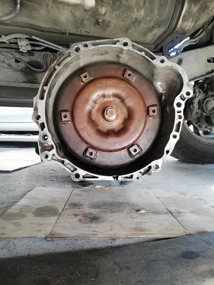 The underside of a vehicle with the automatic gearbox removed, exposing the torque converter and bellhousing