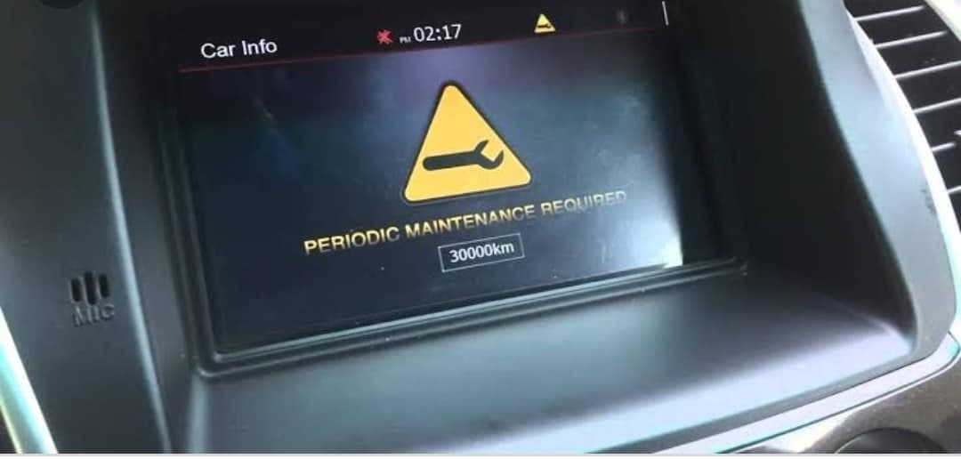 A car dashboard screen showing a spanner warning symbol and the words PERIODIC MAINTENANCE REQUIRED at 30000km